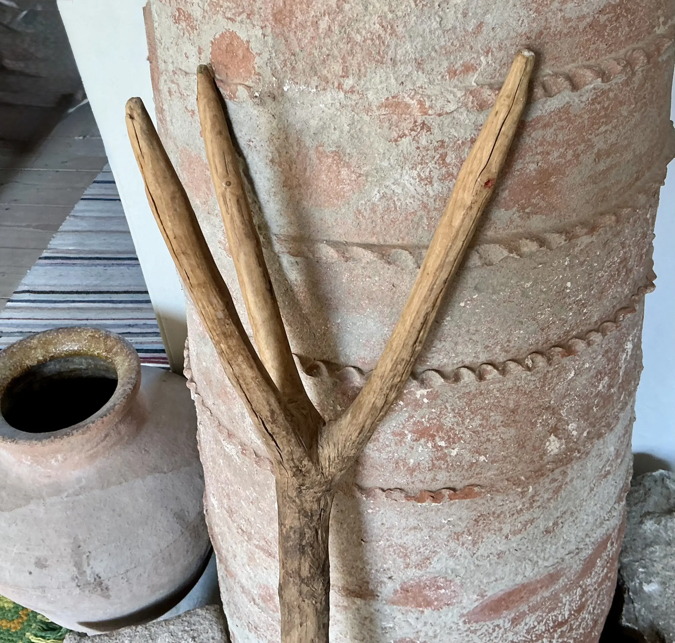 Y-shaped wooden stick beside large clay pot