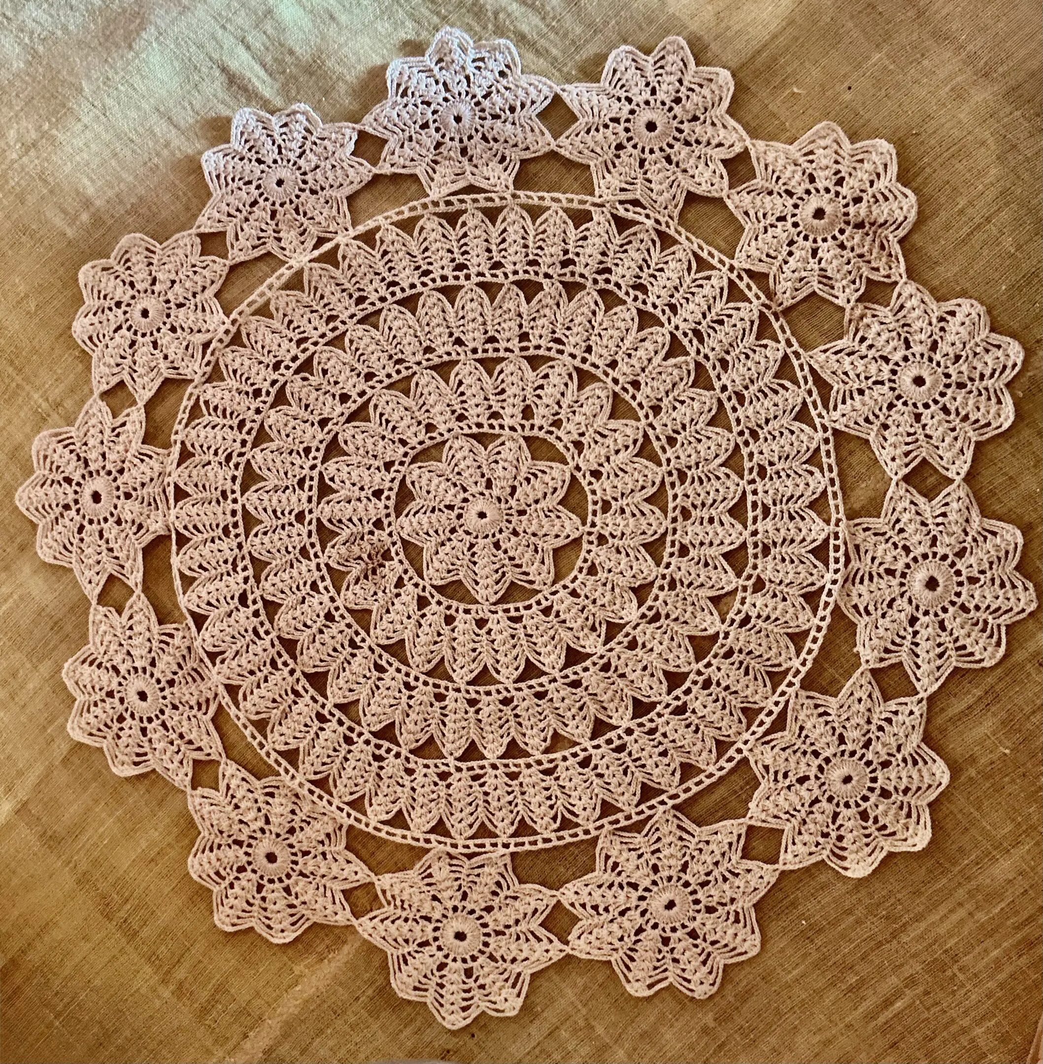 Pink floral crocheted round doily on fabric