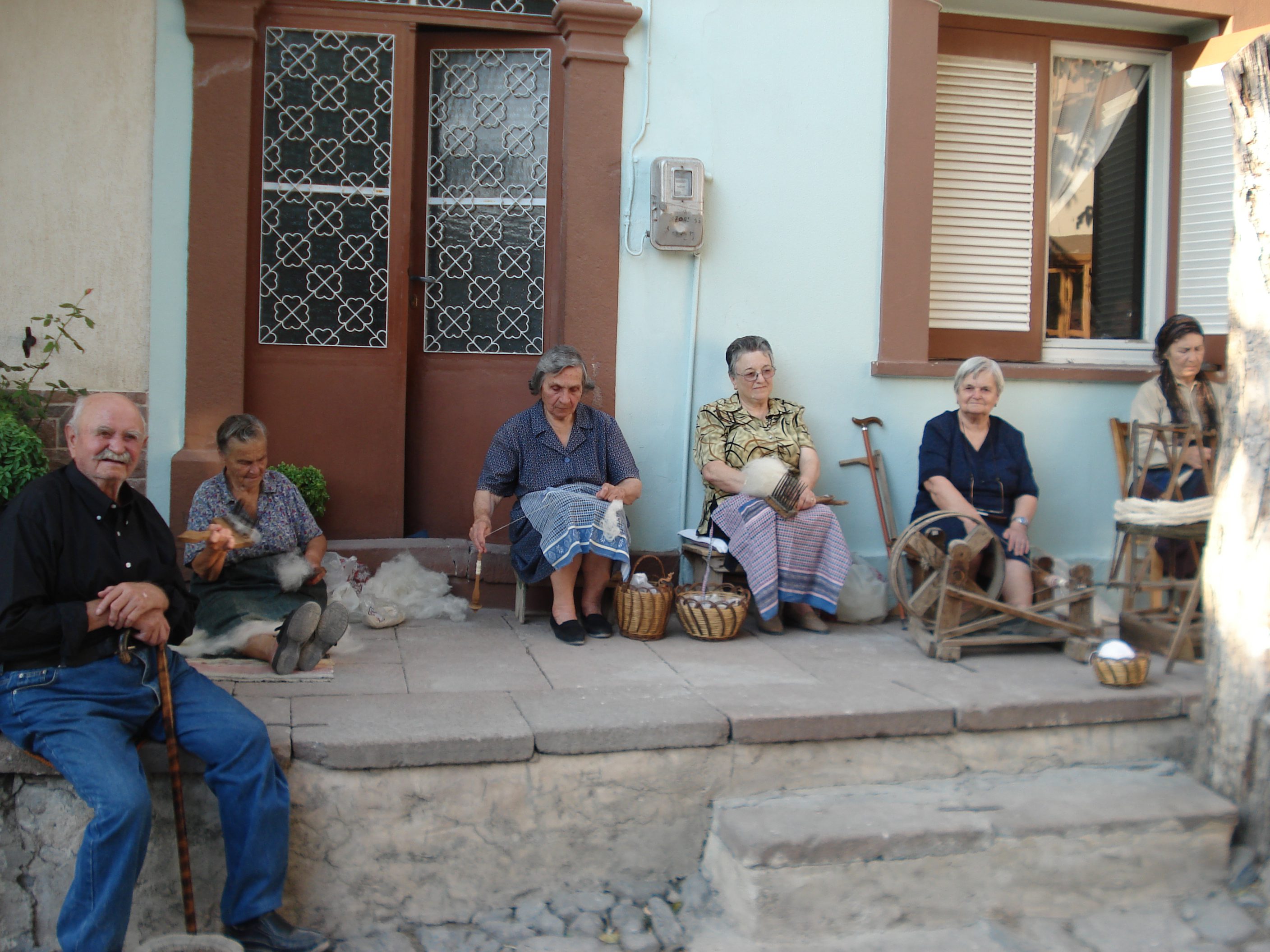 Elderly people sitting on doorstep with baskets